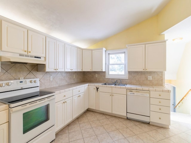 780 Iowa Ave, Martensdale, IA 50160 - kitchen with white appliances, under cabinet range hood, vaulted ceiling, tasteful backsplash, and tile counters