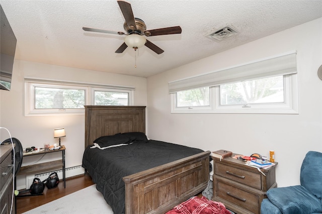 729 SE 3rd St, Ankeny, IA 50021 - bedroom featuring wood finished floors, a baseboard radiator, a textured ceiling, and ceiling fan