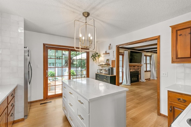 10438 Donna Bella Cir, Clive, IA 50325 - kitchen featuring light wood-type flooring, a fireplace, a chandelier, brown cabinetry, and healthy amount of natural light