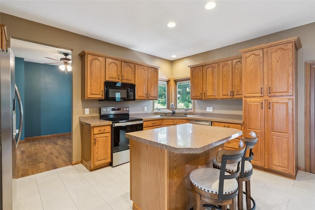 303 Trevor Ct, Norwalk, IA 50211 - kitchen with stainless steel appliances, a kitchen breakfast bar, a center island, light countertops, and recessed lighting