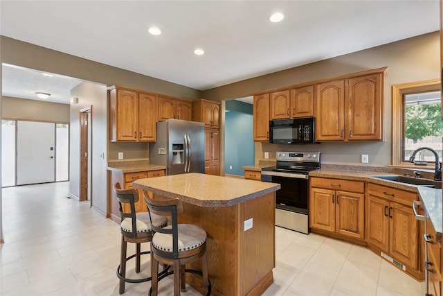 303 Trevor Ct, Norwalk, IA 50211 - kitchen with appliances with stainless steel finishes, a kitchen island, a breakfast bar, brown cabinets, and recessed lighting