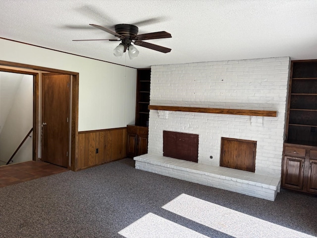 3909 75th St, Urbandale, IA 50322 - unfurnished living room featuring a textured ceiling, carpet floors, ceiling fan, wood walls, and a wainscoted wall