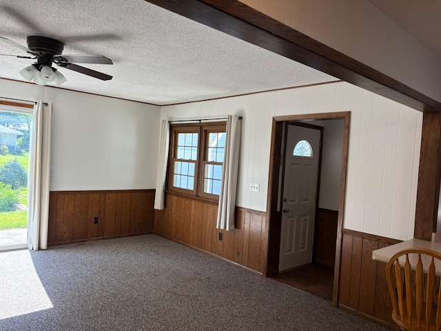 3909 75th St, Urbandale, IA 50322 - foyer entrance with wood walls, healthy amount of natural light, a ceiling fan, a wainscoted wall, and a textured ceiling