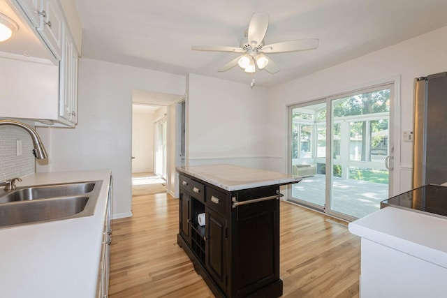 4511 67th St, Urbandale, IA 50322 - kitchen with dark cabinetry, light wood finished floors, a ceiling fan, light countertops, and tasteful backsplash