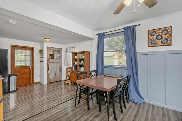 404 W Salem Ave, Indianola, IA 50125 - dining space featuring wood finished floors, a textured ceiling, a wainscoted wall, a ceiling fan, and a decorative wall