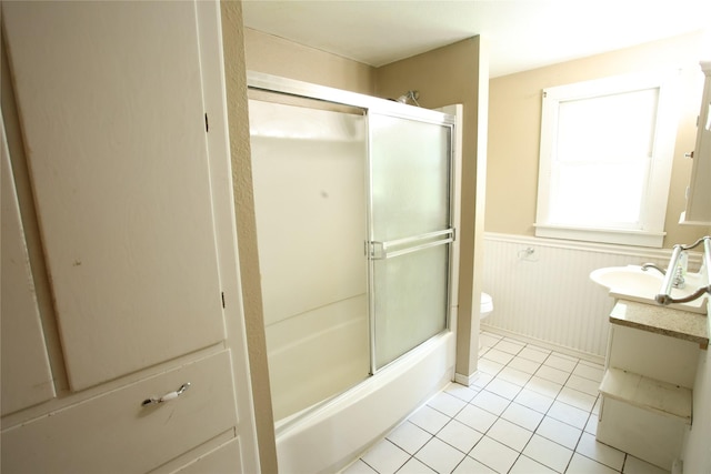 24388 250th St, Eldora, IA 50627 - bathroom with wainscoting, vanity, tile patterned flooring, and shower / bath combination with glass door