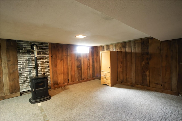 24388 250th St, Eldora, IA 50627 - finished below grade area featuring a wood stove, carpet floors, wooden walls, and a textured ceiling