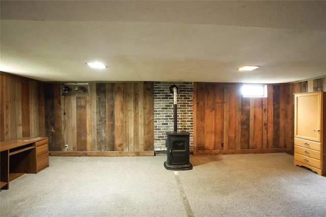 24388 250th St, Eldora, IA 50627 - below grade area featuring wood walls, carpet floors, and a wood stove