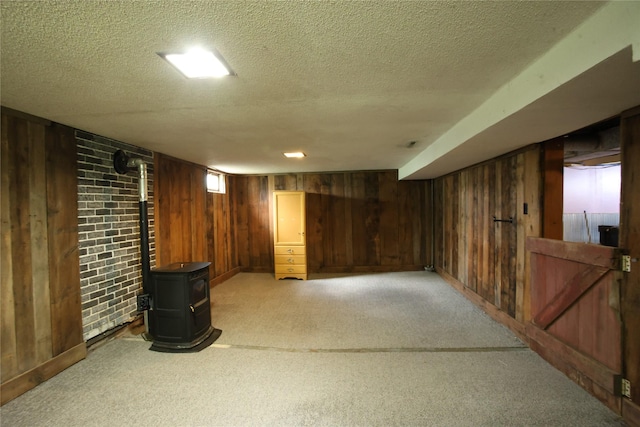 24388 250th St, Eldora, IA 50627 - below grade area with wood walls, a wood stove, light colored carpet, and a textured ceiling