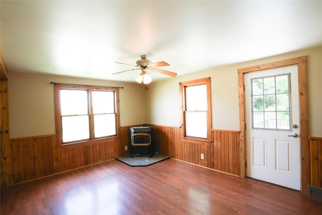 24388 250th St, Eldora, IA 50627 - foyer entrance with wainscoting, a wood stove, wood finished floors, wood walls, and ceiling fan