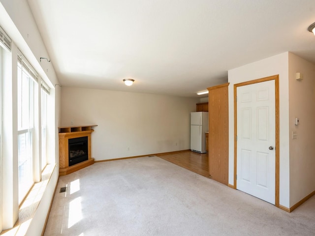 1246 SE Village View Ln, Ankeny, IA 50021 - unfurnished living room featuring light colored carpet and a glass covered fireplace