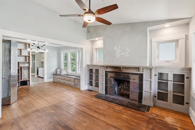 3907 50th St, Des Moines, IA 50310 - unfurnished living room with hardwood / wood-style floors, a ceiling fan, a tile fireplace, and a chandelier