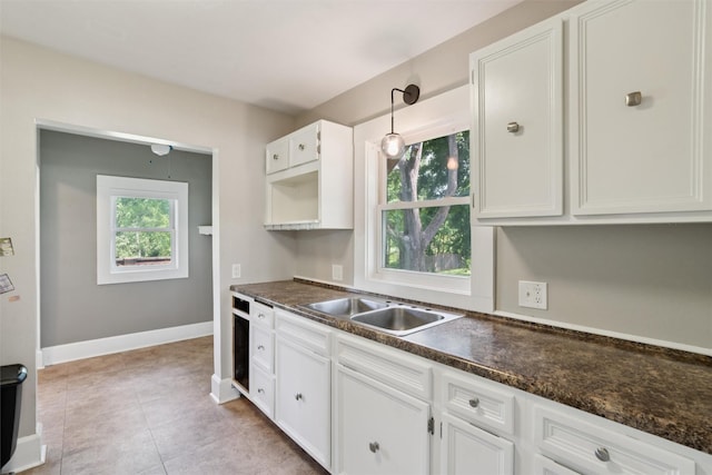 3907 50th St, Des Moines, IA 50310 - kitchen featuring dark countertops, white cabinetry, light tile patterned floors, and pendant lighting
