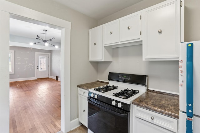 3907 50th St, Des Moines, IA 50310 - kitchen featuring range with gas stovetop, dark countertops, light wood finished floors, and white cabinetry