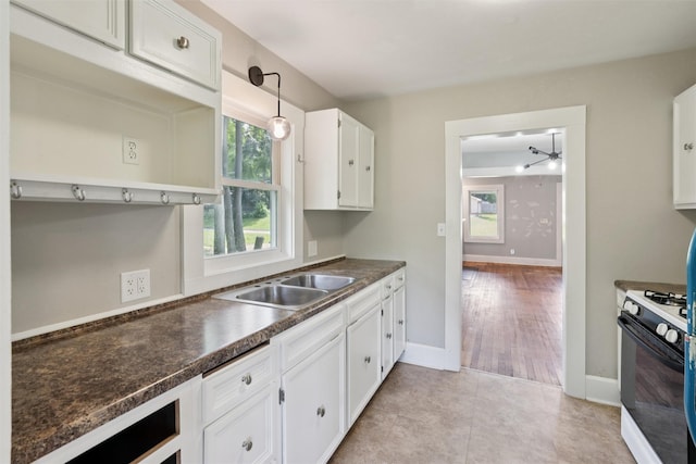 3907 50th St, Des Moines, IA 50310 - kitchen with range with gas stovetop, dark countertops, white cabinetry, pendant lighting, and light tile patterned floors
