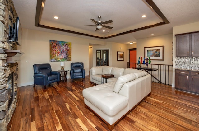 2100 NW Prairie Creek Dr, Grimes, IA 50111 - living room featuring a raised ceiling, wood finished floors, a ceiling fan, a fireplace, and recessed lighting