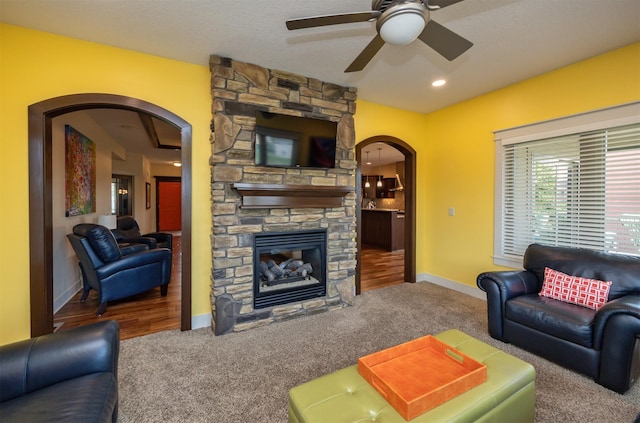 2100 NW Prairie Creek Dr, Grimes, IA 50111 - living area with arched walkways, carpet flooring, a ceiling fan, and a stone fireplace