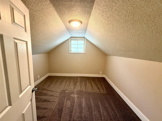 906 Rittenhouse St, Des Moines, IA 50315 - additional living space with a textured ceiling, dark colored carpet, and vaulted ceiling