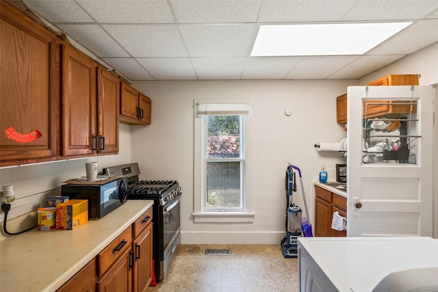 121 Cherry Ave, Ames, IA 50010 - kitchen featuring stainless steel gas range oven, light countertops, brown cabinetry, black microwave, and a paneled ceiling