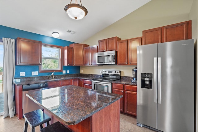 16215 Monroe Ct, Urbandale, IA 50323 - kitchen featuring appliances with stainless steel finishes, lofted ceiling, a kitchen breakfast bar, light tile patterned floors, and dark stone counters