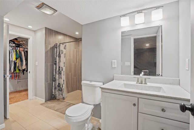 16215 Monroe Ct, Urbandale, IA 50323 - bathroom with vanity, tiled shower, recessed lighting, a spacious closet, and a textured ceiling