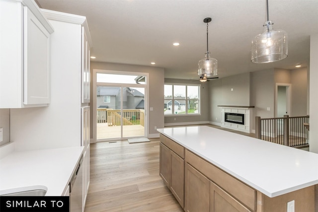 1435 Locust St, Waukee, IA 50263 - kitchen featuring a ceiling fan, light wood-type flooring, a glass covered fireplace, recessed lighting, and light countertops