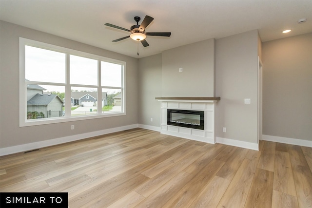 1435 Locust St, Waukee, IA 50263 - unfurnished living room with light wood-style flooring, a ceiling fan, a glass covered fireplace, and recessed lighting