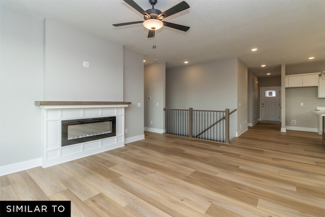 1435 Locust St, Waukee, IA 50263 - unfurnished living room featuring light wood finished floors, a glass covered fireplace, a ceiling fan, and recessed lighting