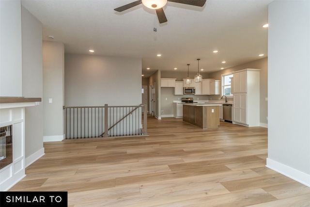 1435 Locust St, Waukee, IA 50263 - kitchen with appliances with stainless steel finishes, white cabinetry, a ceiling fan, open floor plan, and light wood finished floors