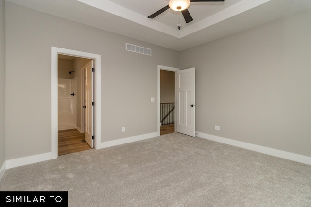 1435 Locust St, Waukee, IA 50263 - unfurnished bedroom featuring carpet floors, a raised ceiling, ceiling fan, and connected bathroom