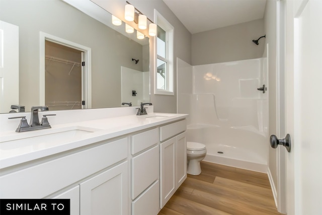 1435 Locust St, Waukee, IA 50263 - bathroom featuring double vanity, wood finished floors, a spacious closet, and a shower