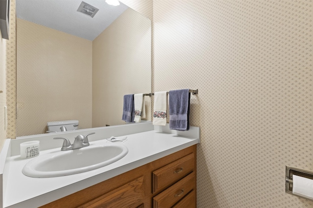 2207 Buchanan Dr, Ames, IA 50010 - half bath with vanity, vaulted ceiling, and wallpapered walls