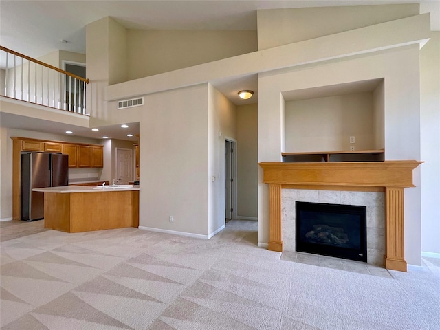 1406 SE Williams Ct, Waukee, IA 50263 - unfurnished living room featuring light colored carpet, high vaulted ceiling, and a premium fireplace