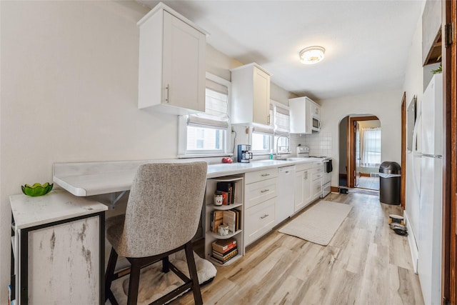 705 Prairie St, Adel, IA 50003 - kitchen with white appliances, arched walkways, light wood finished floors, and white cabinets