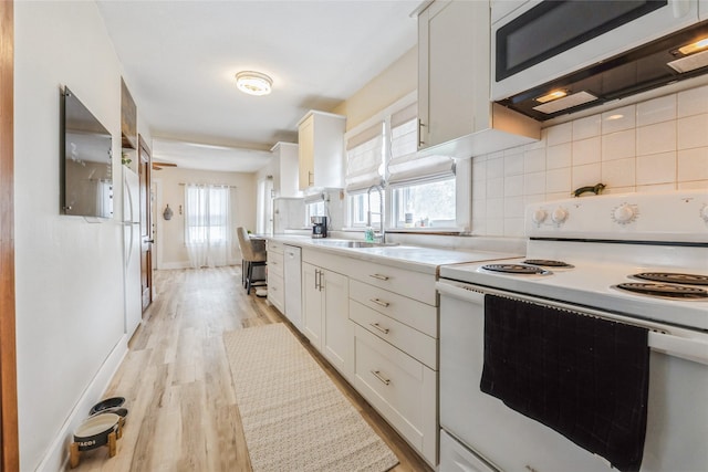 705 Prairie St, Adel, IA 50003 - kitchen featuring white appliances, light countertops, white cabinets, and decorative backsplash