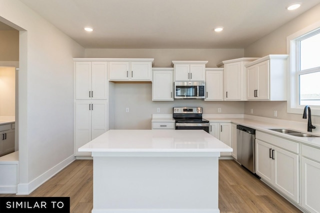 1425 Locust St, Waukee, IA 50263 - kitchen with appliances with stainless steel finishes, white cabinets, a kitchen island, light wood-style flooring, and recessed lighting