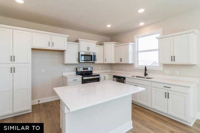 1425 Locust St, Waukee, IA 50263 - kitchen featuring appliances with stainless steel finishes, white cabinetry, a center island, light wood-style floors, and recessed lighting
