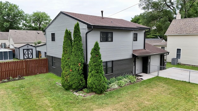 205 E Livingston Ave, Des Moines, IA 50315 - back of house featuring concrete driveway, a storage shed, roof with shingles, and a garage