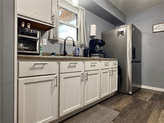 205 E Livingston Ave, Des Moines, IA 50315 - kitchen with stainless steel fridge, white cabinets, dark wood-type flooring, and a textured ceiling