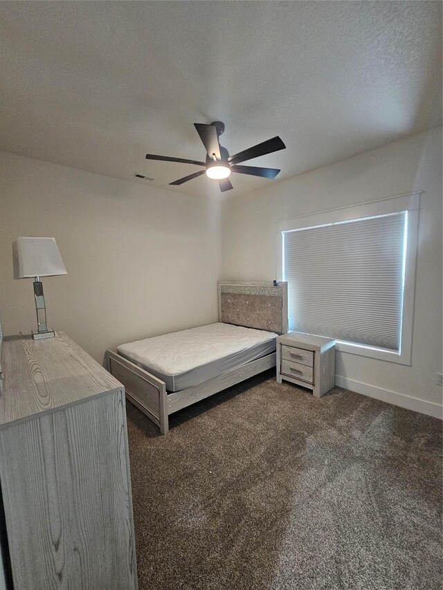 1108 28th St, Perry, IA 50220 - bedroom featuring dark carpet, a ceiling fan, and a textured ceiling