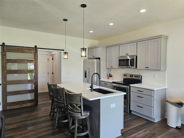 1108 28th St, Perry, IA 50220 - kitchen featuring stainless steel appliances, gray cabinetry, a barn door, dark wood-style floors, and a textured ceiling