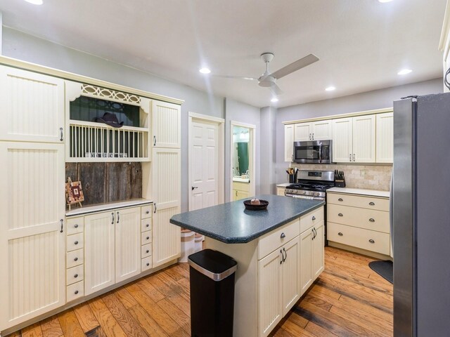 310 Greene St, Boone, IA 50036 - kitchen with stainless steel appliances, ceiling fan, light wood finished floors, dark countertops, and decorative backsplash