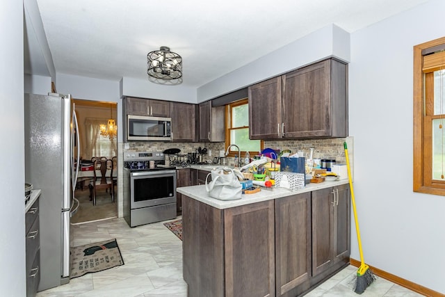 2908 Woodland Ave, West Des Moines, IA 50266 - kitchen featuring appliances with stainless steel finishes, dark brown cabinetry, backsplash, and light countertops