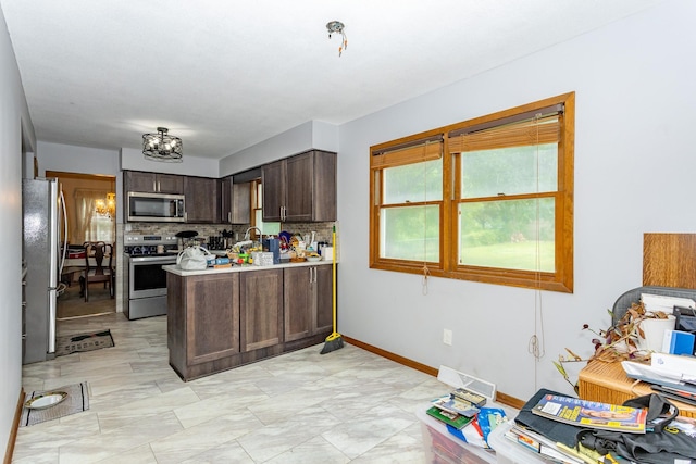 2908 Woodland Ave, West Des Moines, IA 50266 - kitchen featuring appliances with stainless steel finishes, a peninsula, backsplash, dark brown cabinets, and light countertops