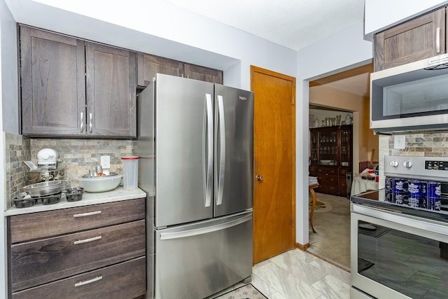 2908 Woodland Ave, West Des Moines, IA 50266 - kitchen with appliances with stainless steel finishes, decorative backsplash, light countertops, light marble finish flooring, and dark brown cabinetry