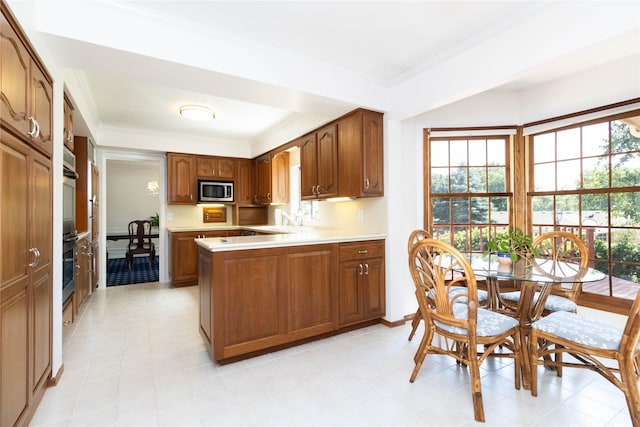 1809 79th St, Windsor Heights, IA 50324 - kitchen featuring stainless steel microwave, light countertops, ornamental molding, a peninsula, and brown cabinets