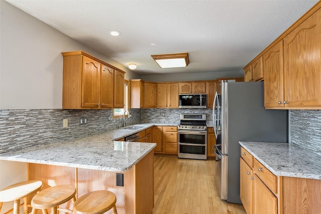 4380 Ashley Park Dr, West Des Moines, IA 50265 - kitchen with stainless steel appliances, a peninsula, light stone countertops, backsplash, and light wood-style flooring