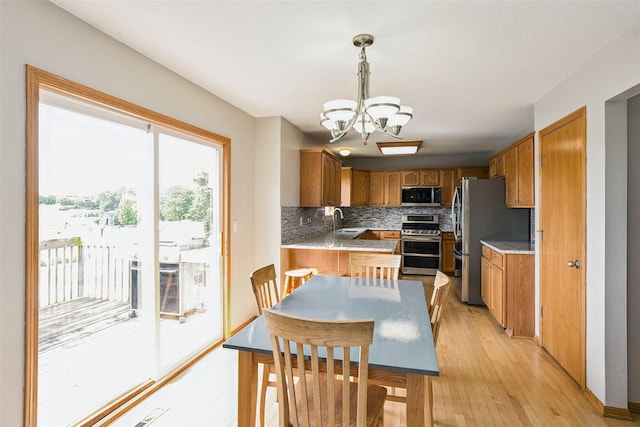4380 Ashley Park Dr, West Des Moines, IA 50265 - kitchen featuring appliances with stainless steel finishes, a chandelier, tasteful backsplash, light wood-style floors, and brown cabinetry