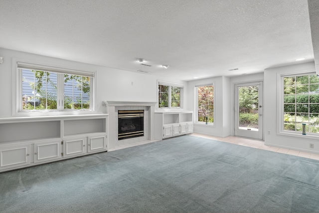 904 54th St, West Des Moines, IA 50266 - unfurnished living room with a textured ceiling, plenty of natural light, carpet flooring, and a tiled fireplace