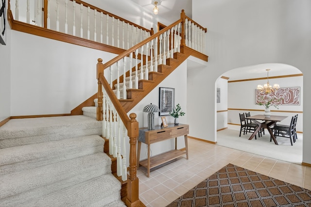 904 54th St, West Des Moines, IA 50266 - stairway featuring arched walkways, a high ceiling, a chandelier, and tile patterned floors